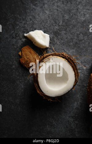 Schließen Sie herauf Bild von gerissenen Coconut auf dunkel strukturierten Hintergrund. Weiches Licht. Stockfoto