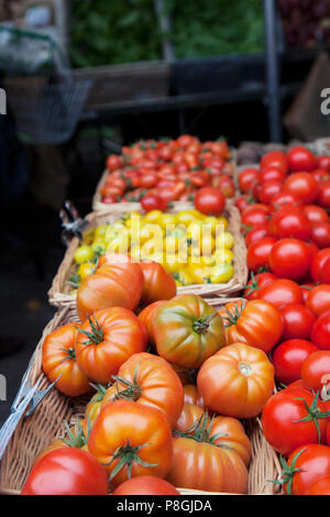 Gemischte Tomaten in Körben auf Marktstand Stockfoto