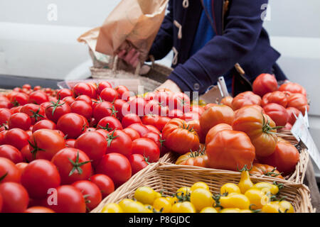 Person Wahl Tomaten aus Körben auf Marktstand Stockfoto