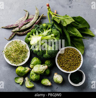 Gesunde Grün essen Sauber Essen auswahl Eiweißquelle für Vegetarier: Rosenkohl, Brokkoli, Spinat, spirulina auf grauem Beton Hintergrund Stockfoto