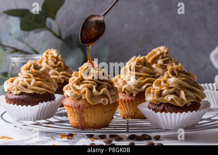 Frische hausgemachte Kuchen mit Kaffee buttercream und Gießen vom Löffel caramel stehend auf Kühlung Rack mit Eukalyptus Zweig und Kaffeebohnen Stockfoto