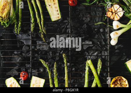 Gegrilltes Gemüse grüner Spargel, Knoblauch, Zitrone, Frühlingszwiebeln, Zucchini, Tomaten, Salat auf BBQ Grill Rack über Kohle. Ansicht von oben, Platz. Ba Stockfoto