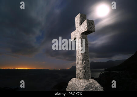 Beängstigend, steinernen Kreuz bei Nacht mit Mond und Wolken im Hintergrund zu sehen. Stockfoto