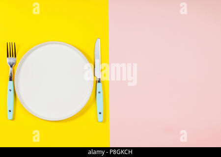 Flach der weissen Teller, Messer und Gabel auf zwei Farbe Pastell Hintergrund Stockfoto