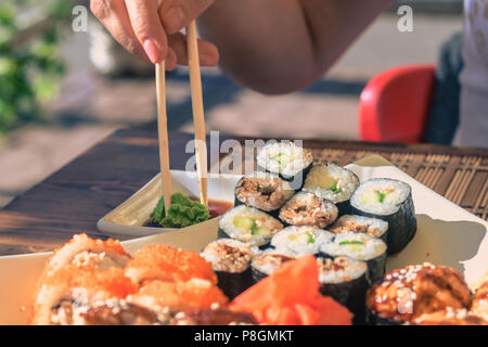 Frau mit Japan sticks isst Sushi in Street Cafe Stockfoto