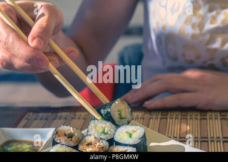 Frau mit Japan sticks isst Sushi in Street Cafe Stockfoto