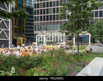 Touristen und einheimische Arbeitnehmer genießen einen sonnigen Sommer Mittagessen in St. Helen's Piazza, London. St Helen's Turm & Leadenhall Building. Blumenbeete, Bäume Stockfoto