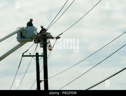 Die Mitarbeiter in einem Cherry Picker Arbeiten an Leitungen Stockfoto