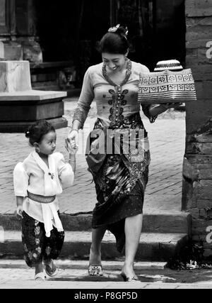 Balinesische Frau und Tochter tragen Angebote indie Hindu Tempel Pura DESA während des Fest Galungan FESTIVAL - Ubud, Bali, Indonesien Stockfoto