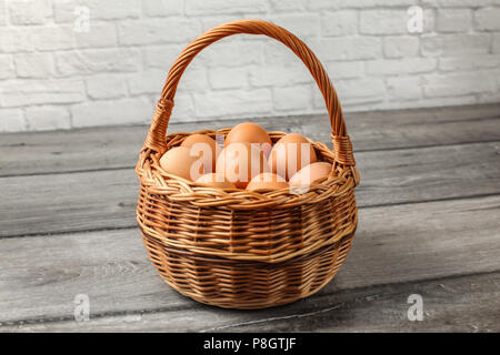 Eier in Weidenkorb auf grau Holz Schreibtisch an der Wand platziert. Stockfoto