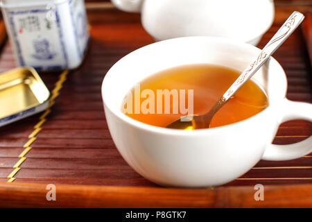 Weißes Porzellan Tasse heißen dampfenden Tee, mit Löffel, platziert auf Bambus Fach. Stockfoto