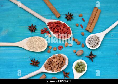 Konzept der Tabelle mit bunten aromatischen Samen und Früchte in Holzlöffel, auf blauem Hintergrund, Flach, obere Tabelle Stockfoto