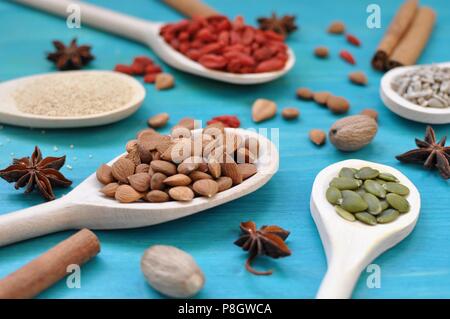 Konzept der Tabelle mit aromatischen Gewürzen Samen und Früchte in hölzernen Löffel auf blauem Hintergrund, Nahaufnahme, selektiver Fokus Stockfoto