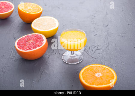 Zitrusfrüchte mit verschiedenen Schichten und Saft in ein Glas. Grauen Stein Hintergrund. Vitamine und Gesundheit in Essen. Platz kopieren Stockfoto