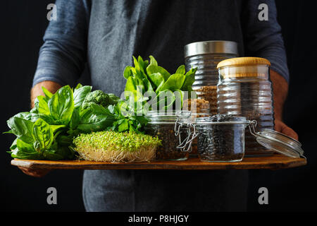 Mann hält gesund essen, Eiweißquelle für Vegetarier: Spinat, Basilikum, Petersilie, Brokkoli, Quinoa, schwarze Bohnen, grüne Linsen, Kichererbsen und buckw eingestellt Stockfoto