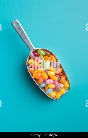 Sweet Jelly Beans in Schaufel auf farbigen Hintergrund. Stockfoto