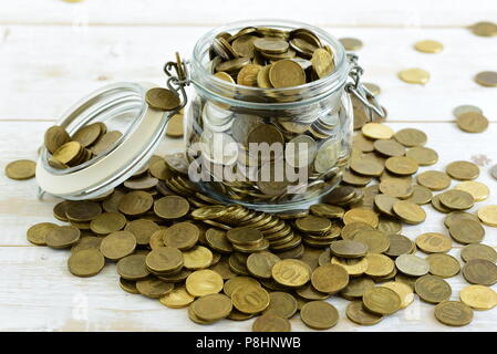 Münzen in einem Glas auf dem Tisch Stockfoto