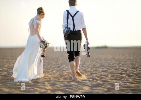 Glückliche Braut und Bräutigam am schönen Strand bei Sonnenuntergang Stockfoto
