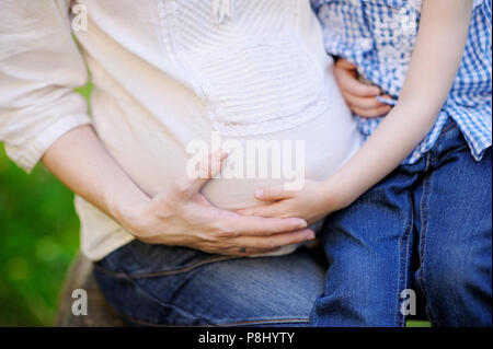 Mutter und Tochter umarmt Hände des schwangeren Bauch Stockfoto