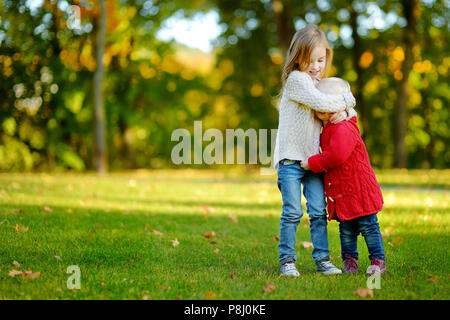 Zwei kleine Schwestern umarmen im schönen Herbst Park an einem sonnigen Tag Stockfoto