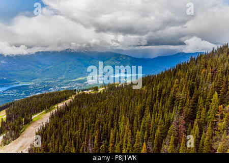 Ein Blick von Oben auf die Landstraße und das Dorf in den Bergen zwischen zwei Seen, von einem dichten Nadelwald, Schnee auf der Oberseite des Mou umgeben Stockfoto