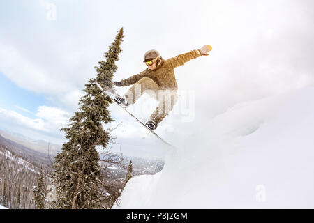 Snowboarder springt von großen schneeverwehung bei offpiste Wald Hang. Freeride Konzept Stockfoto