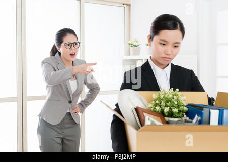 Asiatische Mitarbeiter Vorhaltungen durch den Mittelwert Boss und das Büro verlassen, die Ihr stopft mit hilflos und Low Spirit. Stockfoto