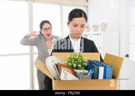 Asiatische Mitarbeiter durch den Mittelwert boss ausgeschimpft schrie und schrie, dass Mitarbeiter im Büro mit Ihrem Finger die resignierte Mitarbeiter hingewiesen. Stockfoto