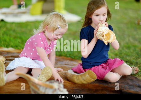 Zwei kleine Schwestern spielen mit Muscheln auf Sommer Tag Stockfoto