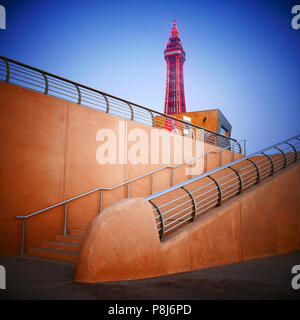 Blackpool Tower, der in der Dämmerung über Betonstufen leuchtet, die vom Meer hinunter führen Stockfoto