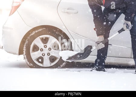 Mann graben Schnee mit Schaufel neben seinem Auto. Stockfoto