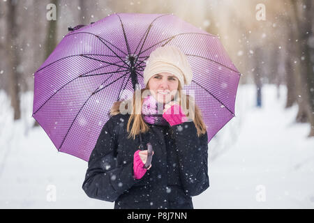 Frau mit Sonnenschirm genießen Sie den Winter im Park. Stockfoto