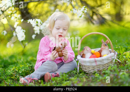 Adorable kleinkind Mädchen Schokolade essen Bunny im Frühling Garten am Ostersonntag Stockfoto