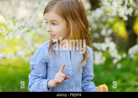 Adorable kleine Mädchen spielen mit Osterei in blühende Frühling Garten am Ostersonntag Stockfoto