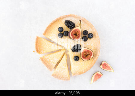 Lemon tart in Scheiben geschnitten und mit frischen Feigen, Heidelbeeren und Brombeeren auf hellgrauem Hintergrund mit Kopie Raum eingerichtet. Ansicht von oben. Stockfoto