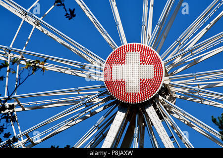 Nahaufnahme von einem Riesenrad in Genf, Schweiz, an der Runde Mittelteil aus rote und weiße Lichter in eine Schweizer Flagge konfiguriert. Stockfoto