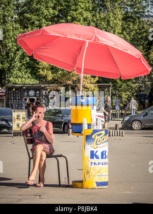 Kiew, Ukraine - August 10, 2015: Mädchen verkauf Kwass (einer beliebten Osteuropäischen Getränk) Ihr smartphone Kontrolle auf einer Straße von der ukrainischen Hauptstadt ci Stockfoto