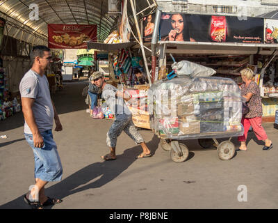 CHISINAU, REPUBLIK MOLDAU - August 11, 2015 Versand: zwei Personen, ein Mann und eine Frau, die Bemühungen Ziehen einer Karre im zentralen Markt der Hauptstadt Stockfoto