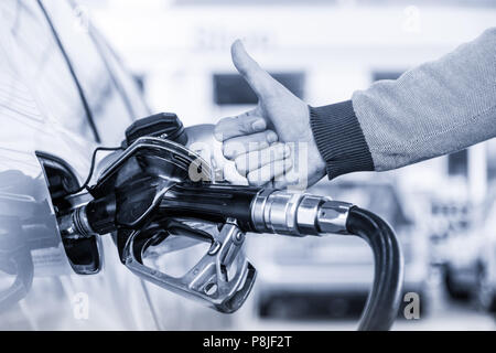 Benzin oder Benzin in ein Kraftfahrzeug Auto gepumpt. Nahaufnahme des Menschen, zeigt Daumen oben Geste, Pumpen Benzin Kraftstoff im Auto an Tankstelle. Stockfoto