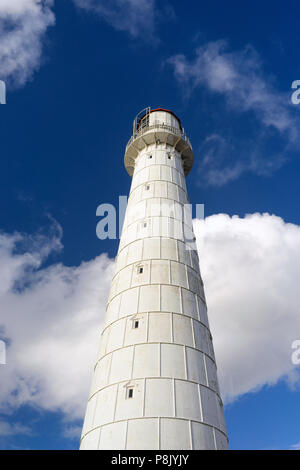 Vintage White Leuchtturm mit kleinen Fenstern und einem roten Dach auf einem Hintergrund von einem blauen Himmel mit weißen Wolken im Sommer. Stockfoto