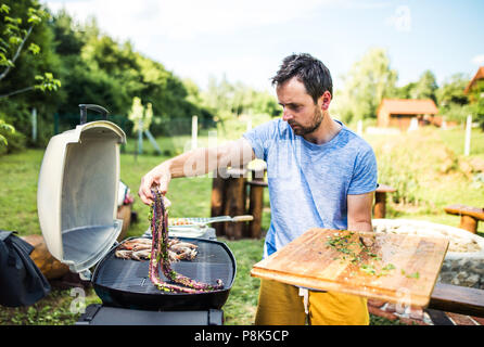 Reifer mann Kochen Fisch auf dem Grill im Hof. Stockfoto