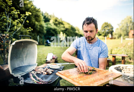 Reifer mann Kochen Fisch auf dem Grill im Hof. Stockfoto