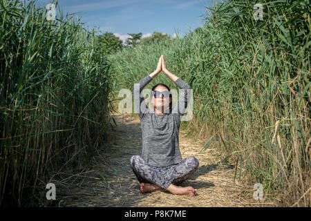 Frau praktizieren von Yoga und Meditation im Freien in einem Feld Stockfoto