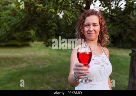 Porträt einer wunderschönen curly Frau mit einem Glas Wein und bieten durch ein Glas Wein. Stockfoto