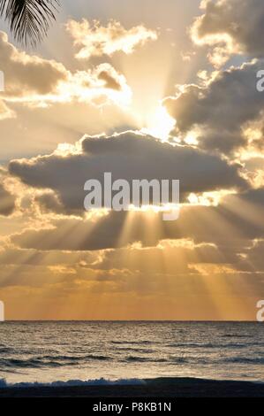 Bunte, teilweise bewölkt orange Sonnenuntergang mit Sonnenstrahlen durchdringen der Wolken über dem Atlantik wie aus Florida, USA gesehen. Stockfoto