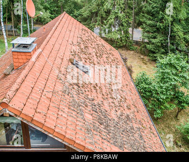 Flug über dem roten Dach eines Einfamilienhauses mit Kamin und eine SAT-Antenne für die Inspektion, Kontrolle und Vorbereitung für eine Reparatur, wi Stockfoto