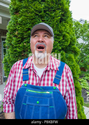 Im mittleren Alter Bauer ein Auge auf das Wetter bis in den Himmel starrte mit offenem Mund und spekulative Ausdruck in der Nähe zu sehen. Stockfoto