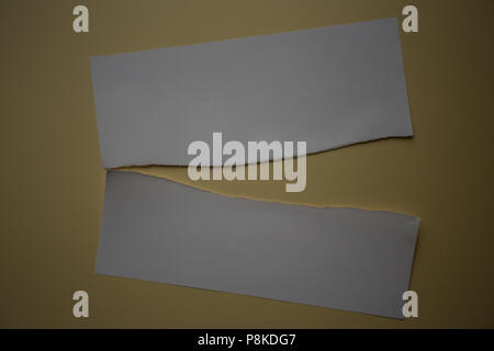 Ein Stück weißes Papier in der Hälfte vor einem gelben Hintergrund zerrissen Stockfoto