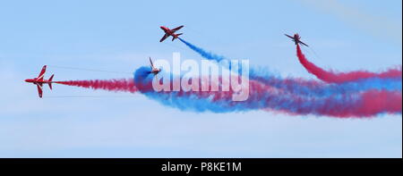 Torbay Airshow, Devon, England: Das RAF Red Arrow-Team bricht die Formation über der Bucht und gibt farbigen Rauch frei. Stockfoto