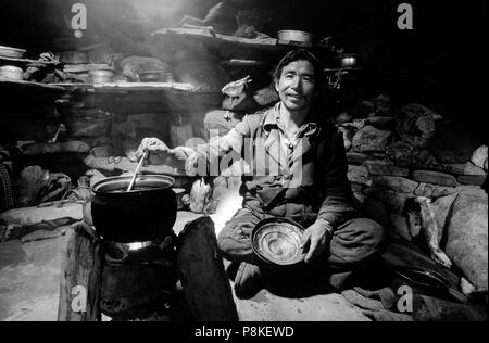 Ein DOLPO MANN KOCHEN mit KÜCHENGERÄTEN in einem Yak herder Hütte - DOLPO BEZIRK, NEPAL Stockfoto